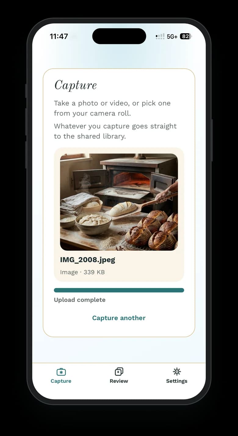 The Wallflower phone app on an iPhone after sending a photo: the bakery photo IMG_2008.jpeg above a full progress bar marked “Upload complete”, with a Capture another link below.